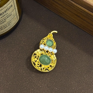 Traditional hollow gold gourd brooch with green jade stones and pearls on velvet