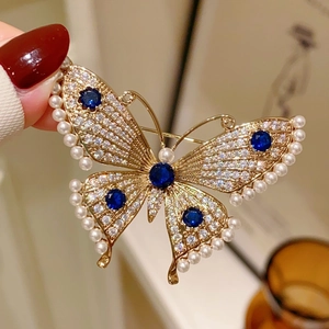 Elegant butterfly brooch with blue stones and pearls on a gold-plated base