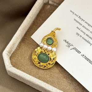 Hollow gold gourd brooch with green gemstones and white pearls in a jewelry box