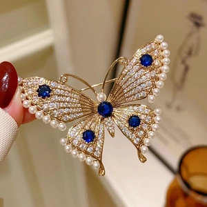 Luxurious butterfly brooch with blue gemstones, pearls and crystals on a gold setting