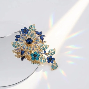 Detailed view of luxury blue crystal floral brooch with elegant golden metal base and stones