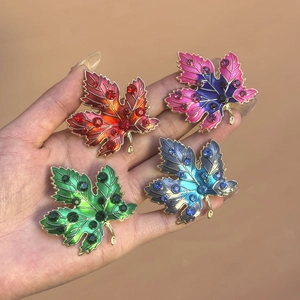 Detail of four maple leaf pins in colorful gradient enamel and sparkling rhinestones