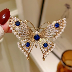 Macro shot of French butterfly brooch with blue crystals and pearl edges on gold metal