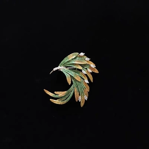 Broche en émail doré et vert en forme de queue de phénix avec cristaux sur fond noir