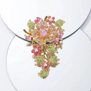 Luxurious flower brooch with pink crystals and green rhinestones in golden setting