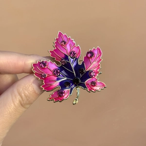 Detail of maple leaf brooch featuring pink gradient enamel and sparkling rhinestones