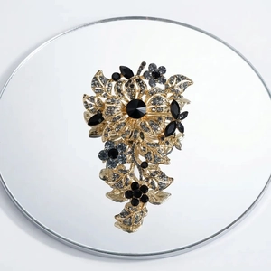 Macro detail of luxury floral brooch with black gemstones and crystals on golden alloy