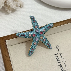 Tropical starfish brooch with colorful rhinestones on a marine style coral display