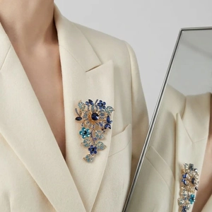 Elegant gold flower brooch with blue crystals pinned on a white blazer lapel