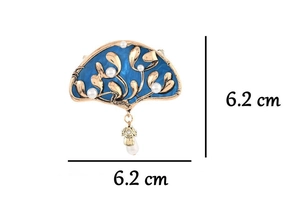 Detailed view of blue enamel fan brooch with gold leaf patterns and white pearls