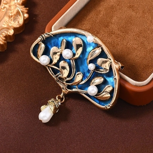 Vintage fan-shaped brooch with blue enamel, gold leaf textures, and white pearl drops