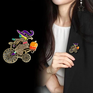 Halloween witch riding bicycle brooch with orange pumpkin and sparkling crystals