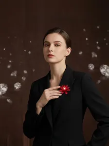 Detailansicht einer roten Lotos-Brosche mit Perle am Revers eines schwarzen Blazers