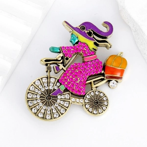 Detailed view of witch on bicycle brooch with enamel pumpkin and crystal accents