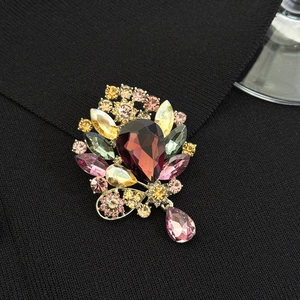 Macro detail of luxury vintage brooch with red crystal teardrop and multicolor rhinestones