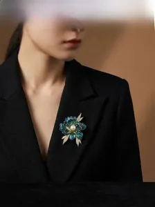 Detail of vintage peony brooch with blue-green enamel and white pearl on black suit
