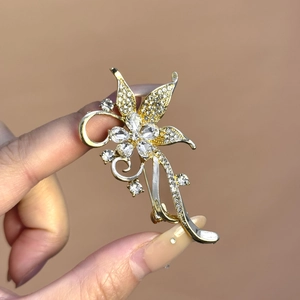 Broche florale de luxe avec zircons scintillants et touches dorées tenue à la main