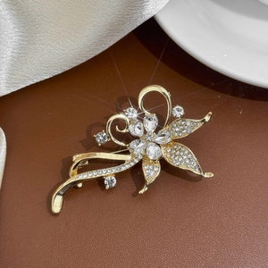 Gros plan sur une broche fleur dorée avec cristaux, zircons et détails de pompons