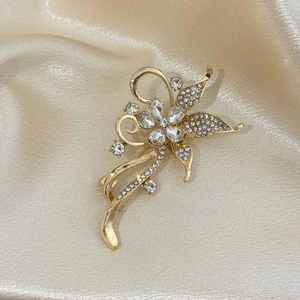 Macro d'une broche florale de luxe avec cristaux clairs sur tissu de soie champagne