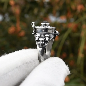 Vista macro dell'anello punk con teschi, coperchio apribile e pietra nera tonda incastonata