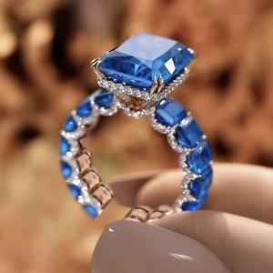 Lujoso anillo de oro rosa con zafiro azul talla esmeralda y doble halo de diamantes