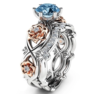 Detail van koppel ring set met blauwe edelsteen en roségouden bloem ontwerp