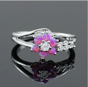 Close-up of pink opal flower ring with a center zircon on a reflective surface