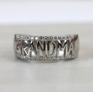Gros plan d'une bague en argent avec lettrage GRANDMA et sertissage de zircons cubiques