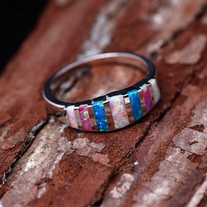 Silver ring with rectangle opal stones in pink and blue on a natural wood bark background