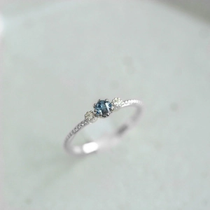 Macro detail of silver ring with sea blue round cut crystal and textured band
