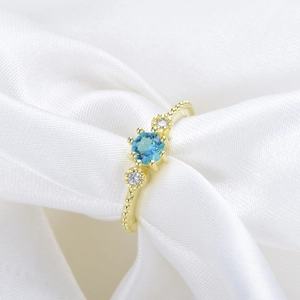 Detailed macro of vintage gold ring featuring a blue gemstone and beaded edge textures