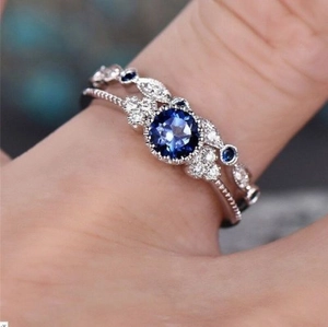 Close-up van een verzilverde ringenset met blauwe edelsteen en micro-ingelegde zirkonia