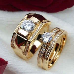Détail d'un ensemble de bagues de couple plaquées or avec zircon sur tissu blanc