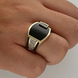 Macro detail of men's gold signet ring with black stone and Greek Key diamond patterns