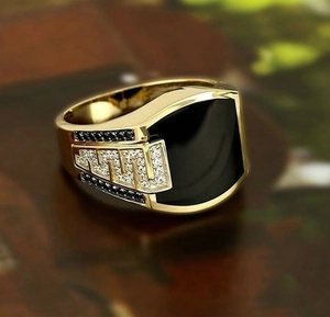 Macro shot of men's gold signet ring with black enamel and diamond accents on side
