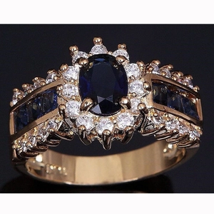Lussuoso anello in oro rosa con grande gemma blu ovale e alone di cristalli bianchi lucidi