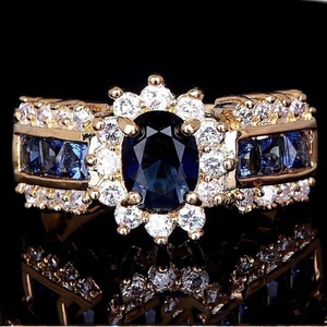 Dettaglio macro dell'anello in oro con pietra blu ovale e zirconi bianchi incastonati