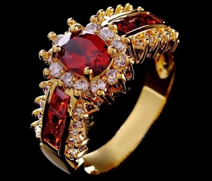 Dettaglio macro di anello d'oro vintage con gemma rossa ovale e diamanti bianchi lucidi