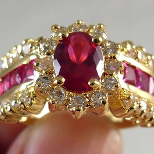 Anello vintage dorato con pietra rossa ovale e alone di cristalli su fascia larga