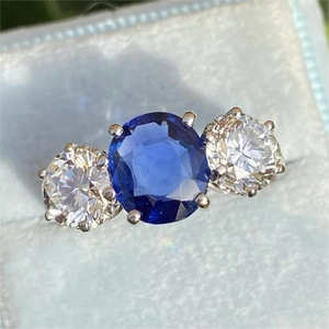 Three-stone sapphire ring in silver finish placed inside a light blue velvet jewelry box