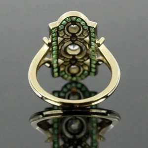 Art Deco emerald engagement ring in gold with diamond accents and geometric openwork