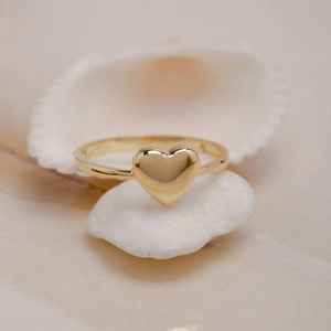 Anillo de corazón dorado minimalista sobre piedras blancas, joyería elegante