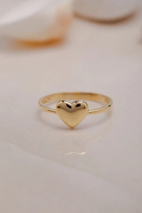Detalle del anillo dorado en forma de corazón con grabado S925 en la banda interior