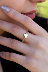 Vista detallada de un anillo de corazón de oro pulido en un dedo con un fondo suave