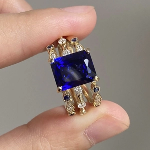 Gouden stapelbare ringenset met grote rechthoekige blauwe edelsteen en microparel-details
