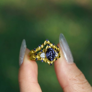 Dettaglio macro dell'anello dorato con zaffiro blu e design a vite con pietre laterali