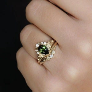 Macro-opname van vergulde kroonring set met groene zirkoon en bloemengravure details