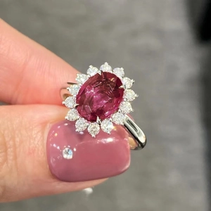 Anello classico in argento con grande zircone rosso ovale e alone scintillante tenuto in mano