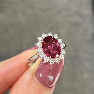 Anello in argento con rubino ovale e halo di diamanti sulla mano della modella