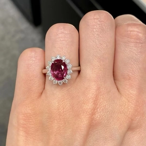 Macro di un anello di lusso con rubino ovale e halo di zirconi in finitura argentata